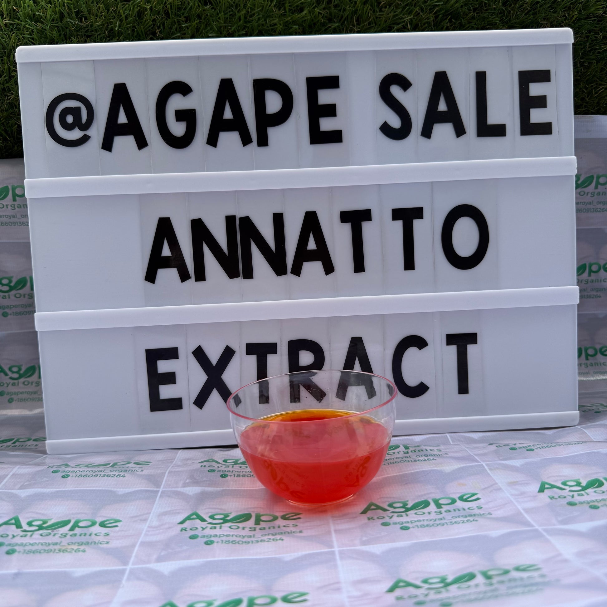 Agape Sale Annatto Extract' text and a glass of red liquid on a branded surface.